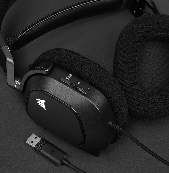 Tai nghe USB HS80 RGB nằm trên một bề mặt phẳng với một bên chụp tai xoay để hiển thị miếng đệm tai bằng mút hoạt tính.
