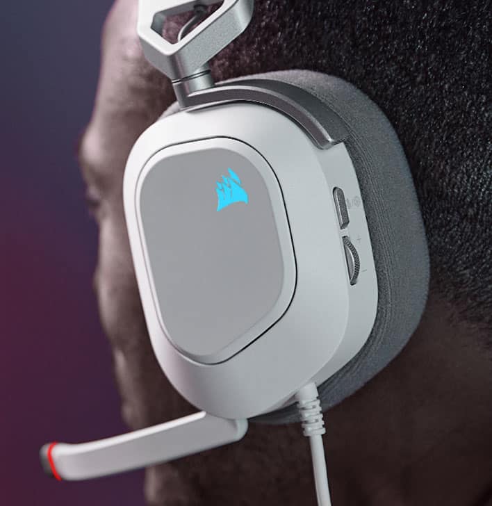 Man wearing HS80 RGB USB wired gaming headset while playing video games with RGB lighting on the Corsair sail logo.